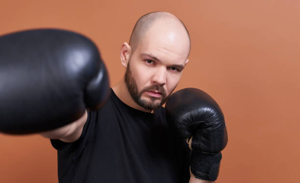 Hook is on the right of a young boxer with a beard. stock photo