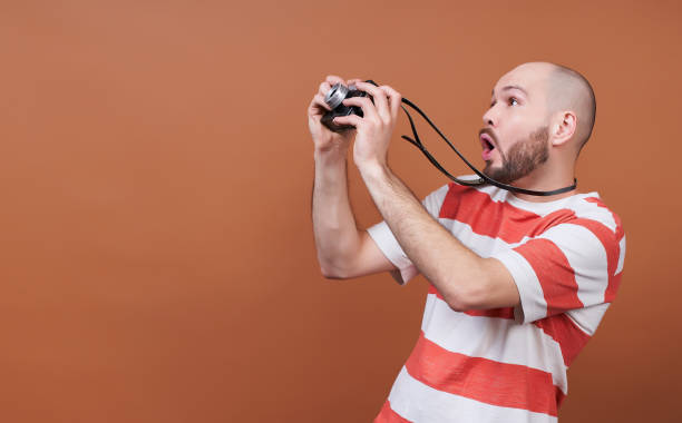 istock Shocked young man takes a picture of something, posing in profile. 1454429708