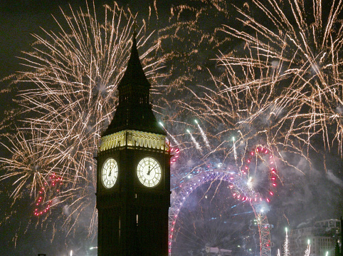 New Years firework hearts in a display set against the iconic London Westminster skyline and Big Ben clock tower showing midnight on new Year's Eve