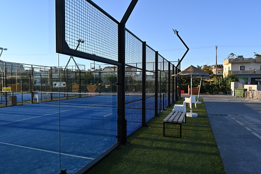 Ammourdara, Greece, 09 20 2022: View on enclosed court for padel with construction created by mesh and the glass back walls. Padel is a racket sport played in doubles and is similar to tennis with the same rules of scoring.