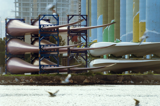 View of windmill wings stacked in seaport.