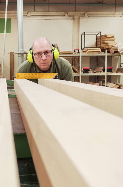un hombre caucásico de 50 años es carpintero, mide y prepara bloques de madera. - herramienta triangular fotografías e imágenes de stock
