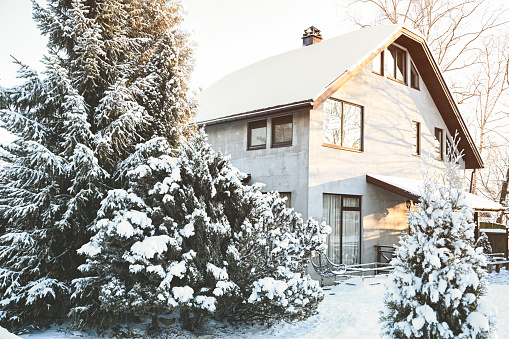 Morning sun rises behind a single family home on Cape Cod decorated for Christmas after a light overnight snowfall