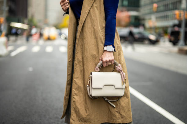 A woman with a smart watch holding a bag on the street of Manhattan during busy working week Close up on businesswoman's hand with a smart watch while holding a bag on the street of New York after finishing work. handbag stock pictures, royalty-free photos & images