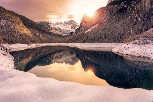 Beautiful snowy winter landscape with Dachstein mountain and Gosausee in Austria near Hallstatt with sun.