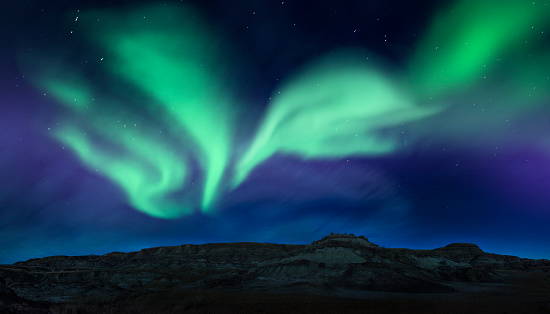 Northern lights above the beautiful landscape of the Canadian Badlands in Drumheller, Alberta, Canada.