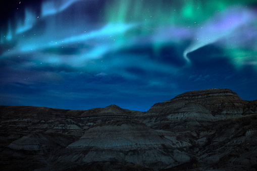 Northern lights above the beautiful landscape of the Canadian Badlands in Drumheller, Alberta, Canada.