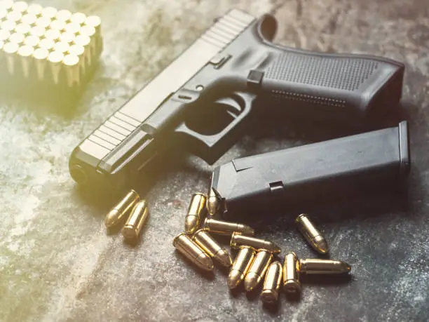 Photo of Hand gun with ammunition on dark background. 9 mm pistol.