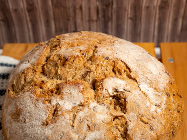 istock Dark bread on a wooden background. Round Bread with grains. 1454442869