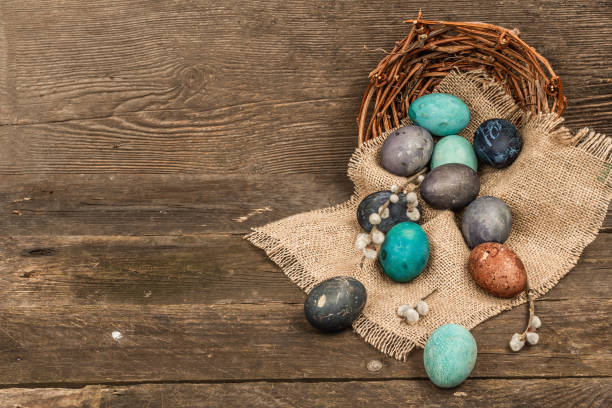 istock Easter eggs in wicker basket and blooming cherry on old wooden background. Festive greeting card 1454444519