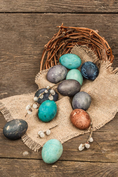 istock Easter eggs in wicker basket and blooming cherry on old wooden background. Festive greeting card 1454444528