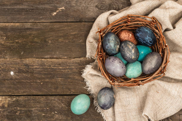 istock Easter eggs in wicker basket and blooming cherry on old wooden background. Festive greeting card 1454444537