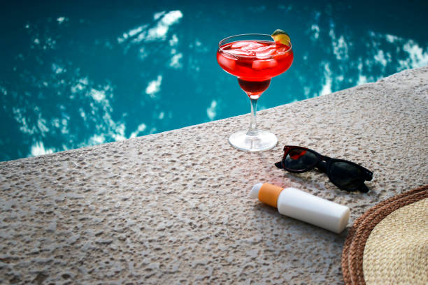 istock refreshing red Cocktail at the pool with sunscreen, sunglasses and straw hat 1454448954