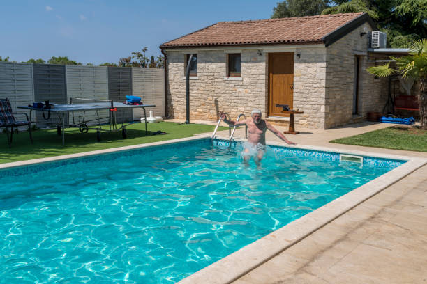 istock Senior men jumping into the swimming pool in villa backyard 1454455227