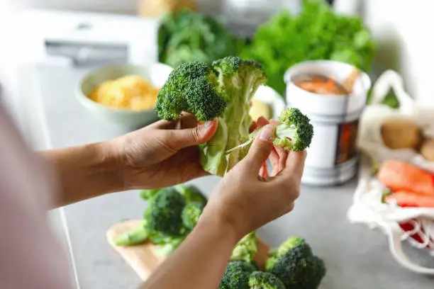 Woman preparing healthy vegetarian food. Cutting vegetables into small pieces.