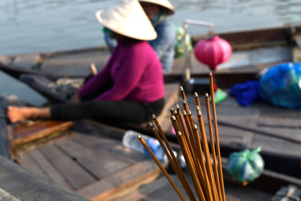 Incense sticks burning, and water taxi boats on the background in Hoi An city.