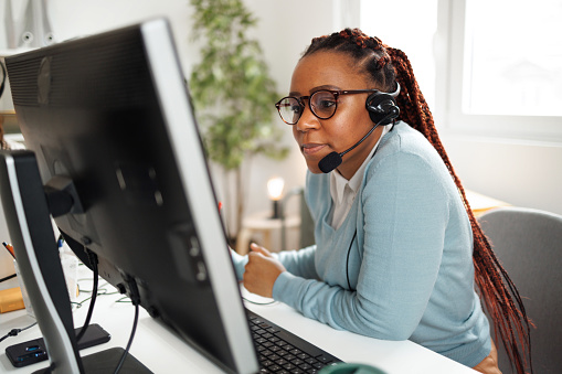 Shot of a young female call center agent working in the home office