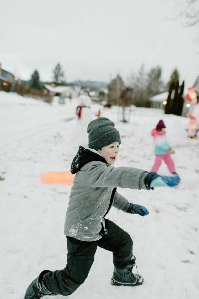 menino que tem luta bola de neve com amigos - snowball snow play throwing - fotografias e filmes do acervo