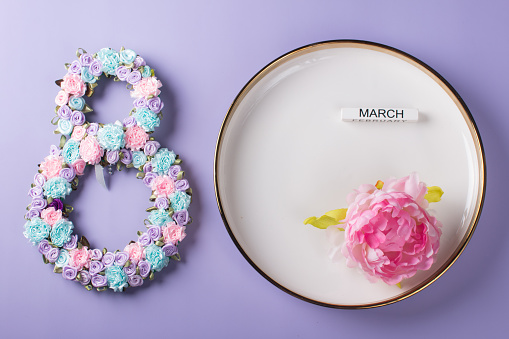 Festive table setting. The number 8 decorated with flowers on a white plate. Congratulations on the International Women's Day on March 8, a festive postcard banner