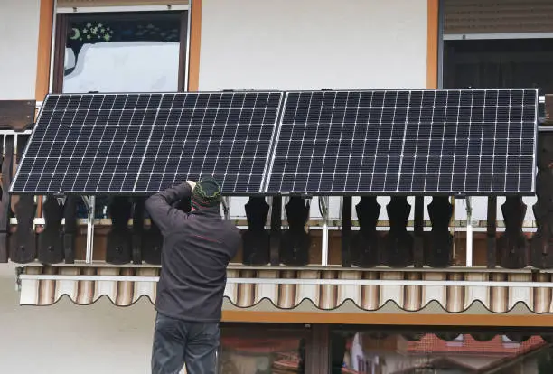 A man assembles a balcony power plant to generate electricity
