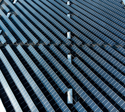 Large solar panel array stacked farm on a distribution warehouse building top down aerial view - realised with a drone