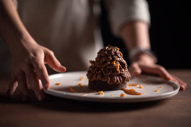 A female chef serving a pine tree-like chestnut tart for Christmas dinner.