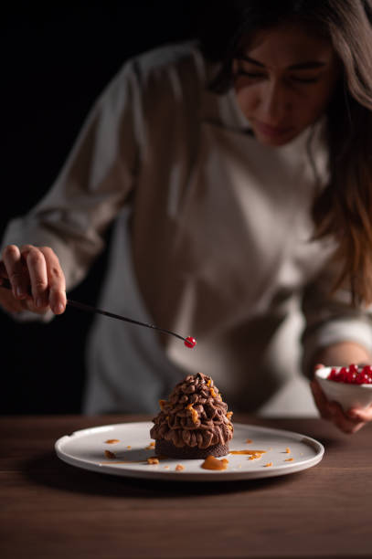 une femme chef décore une tarte au châtaignier ressemblant à un pin - tart dessert chocolate fruit photos et images de collection