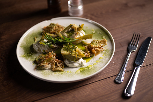 Spicy French snails, escargot cooked with butter, parsley, lemon and garlic close-up on a plate on a table. horizontal