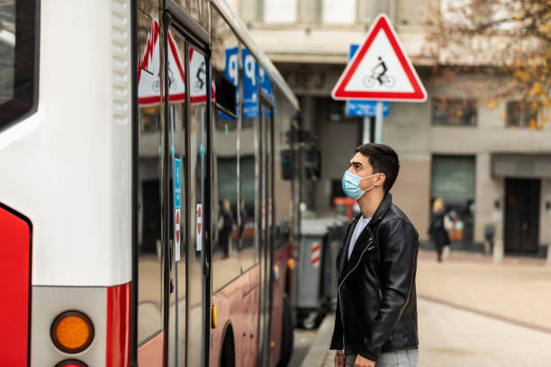 istock A young man with a protective mask on his face enters the bus 1454481921