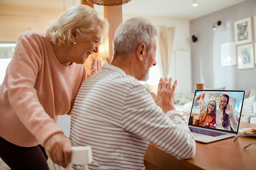 Close up of a senior couple talking to their daughter and granddaughter over a video call