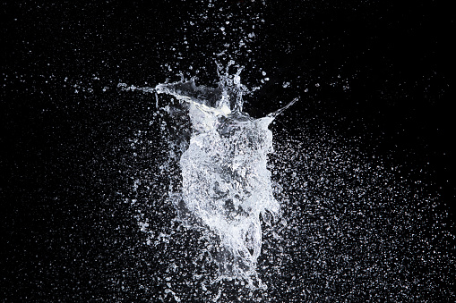 Water balloon explosion splashing in form shape, is power refreshing freshness concept. Waters Balloon explode and droplet spill all around with freeze high speed shot in black background studio