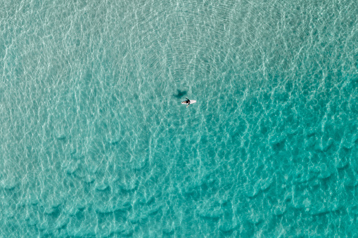 Aerial view of a surfer in the shallow water