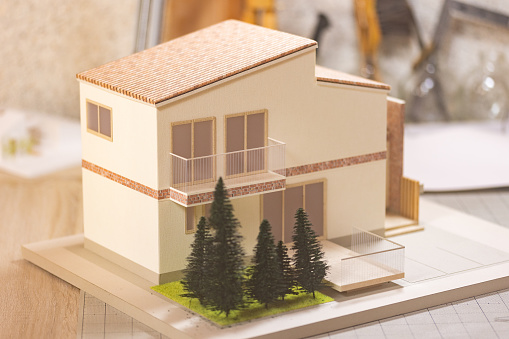 A close up view of a two-story model house on a desk used by architects to show clients the design of a house.