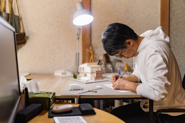 istock A Japanese architect designing a house with a model and blueprints in home office 1454490770