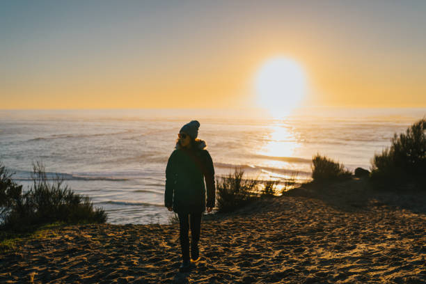 istock Woman enjoying the sunset at the beach 1454497565