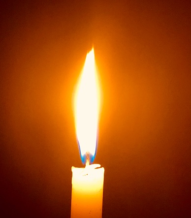 A single lit candle illuminates a Hoboken, New Jersey apartment at night.