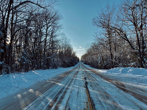 Snowy rural road with surrounding heavily wooded forests taken on a cold but beautiful day during polar vortex temperatures. Taken in Holmes Township, Michigan in The Upper Peninsula.