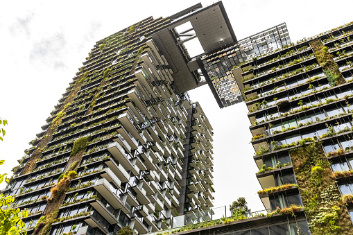 Low angle view of apartment buildings with vertical gardens and heliostat with motorised mirrors, sky background with copy space, Green wall-BioWall or living wall is a wall covered with living plants on residential tower in sunny day, Sydney Australia, full frame horizontal composition