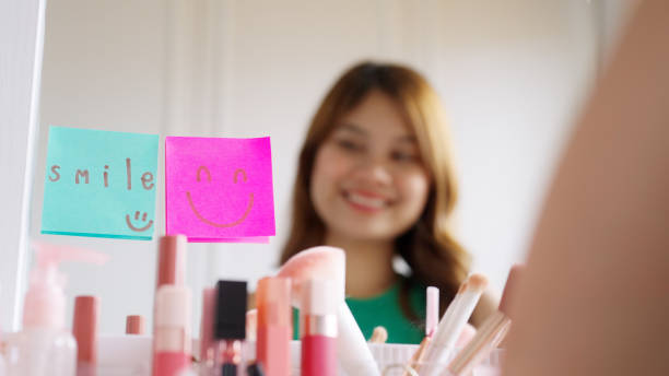 istock Asian woman self talk in front of mirror with smiley sticky note. 1454515883