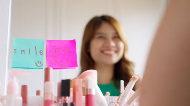 istock Asian woman self talk in front of mirror with smiley sticky note. 1454515885