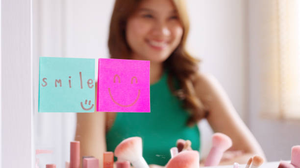 istock Asian woman self talk in front of mirror with smiley sticky note. 1454515887
