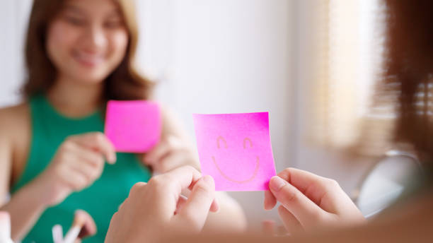 istock Asian woman self talk in front of mirror with smiley sticky note. 1454515898