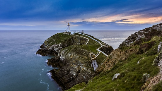 An aerial shot of South Stack Lighthouse under the blue sky at sunset in Wales