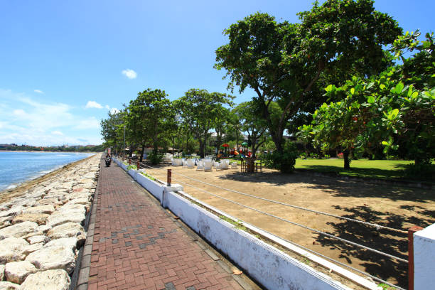 The beach path in Kuta, Bali, Indonesia that runs along the coast between Jerman Beach or Pantai Jerman in Tuban and Kuta. The path is used by walkers, joggers and has views of the beach and sea as well as entry to several hotels on the beach front. el camino de la playa en kuta, bali, indonesia que corre a lo largo de la costa entre jerman beach o pantai jerman en tuban y kuta. el camino es utilizado por caminantes, corredores y tiene vistas a la playa y al mar, así como entrada a varios hoteles en