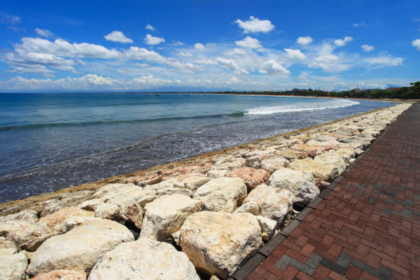 The beach path in Kuta, Bali, Indonesia that runs along the coast between Jerman Beach or Pantai Jerman in Tuban and Kuta. The path is used by walkers, joggers and has views of the beach and seas well as entry to several hotels on the beach front. el camino de la playa en kuta, bali, indonesia que corre a lo largo de la costa entre jerman beach o pantai jerman en tuban y kuta. el camino es utilizado por caminantes, corredores y tiene vistas a la playa y al mar, así como entrada a varios hoteles en