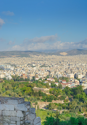 View in Athens of the Temple of Hephaestus among the greenery and buildings in the distance on a sunny day in a vertical format