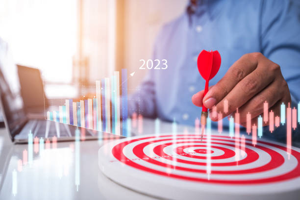 istock Male hand holding darts Aim at the target with business graph on screen , business plan growth year 2023 1454520131