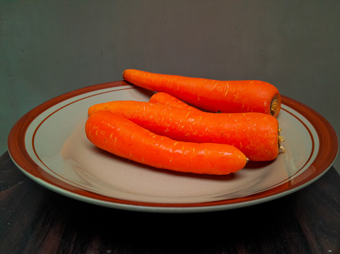 Some orange carrots on a brown ceramic plate