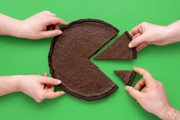 Photo of Pie chart concept, people sharing chocolate cake, above view on a green background.