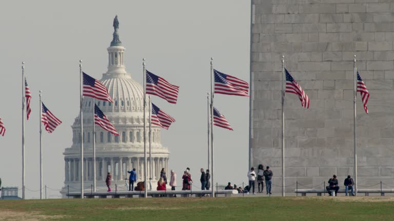 Tourist Stand At Base Of Washington Monument With US Capitol Dome In Distance